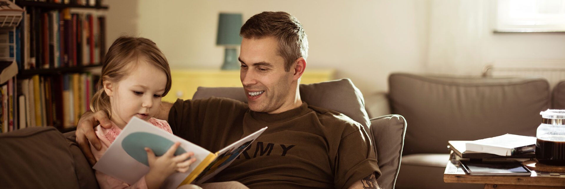 A man sitting on the couch reading a book.